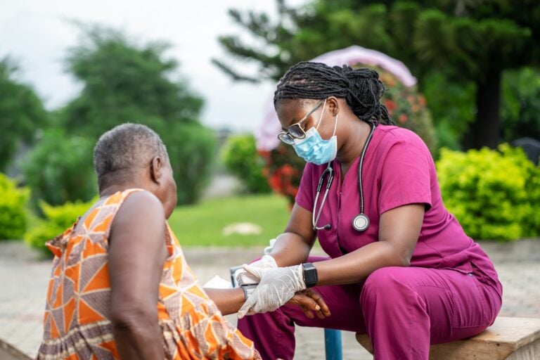 Image,Of,African,Young,Nurse,In,Facemask,,Diagnosing,Senior,Woman