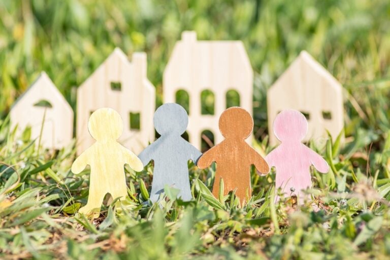 Rural Health Care Coordination - image of wooden people figures holding hands in front of wooden houses.